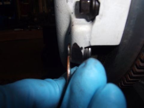 1991 Ford Taurus - Close-up of a hand in a blue glove holding a copper washer near a car's body panel.