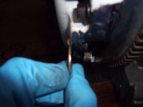 1991 Ford Taurus - Close-up of a gloved hand holding a washer near an engine part and a toothed belt.