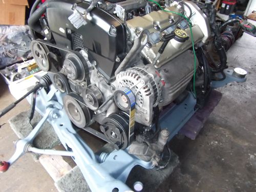 Engine assembly on a stand, showing belts, alternator, and engine cover