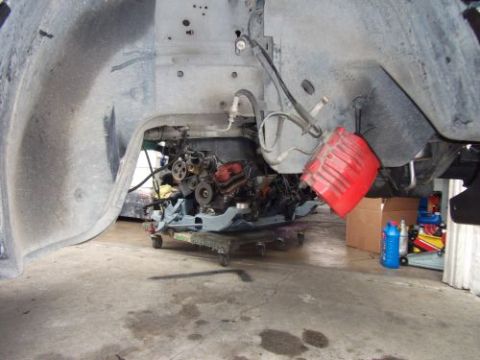 1991 Ford Taurus - An engine is being worked on, supported by a dolly beneath the wheel well of a vehicle.