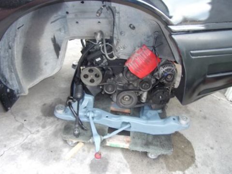 1991 Ford Taurus - The engine bay of a car is shown with the engine removed, revealing suspension components and engine accessories.