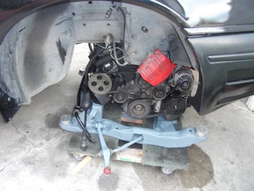 car's engine bay, engine is out, showing suspension parts and engine components like alternator and pulleys