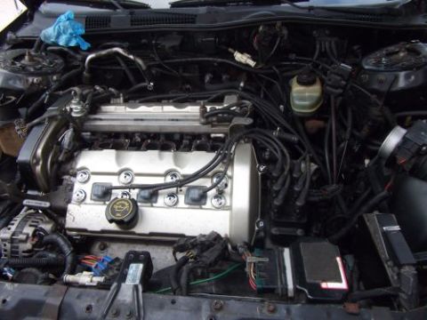 1991 Ford Taurus - The engine bay of a 1991 Ford Taurus SHO is shown, featuring the V6 engine with its distinctive silver valve covers and exposed wiring. Var…