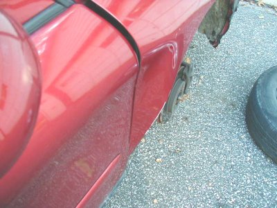 1997 Ford Taurus - A red car is missing a wheel and shows signs of rust and damage.