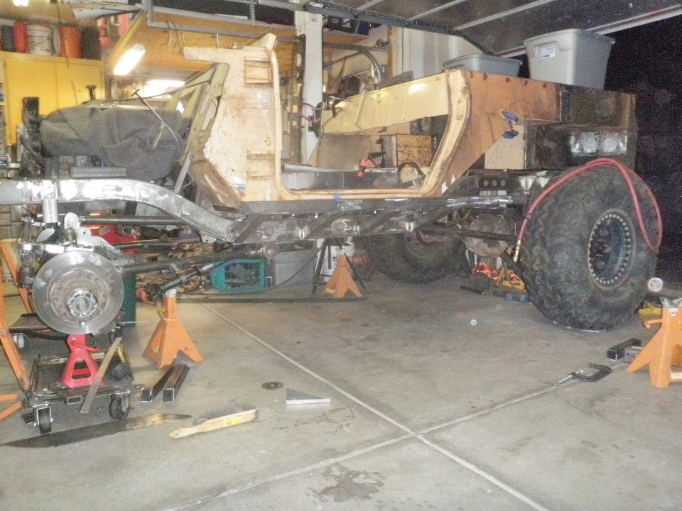 Custom off-road vehicle chassis on jack stands with large tires and exposed frame