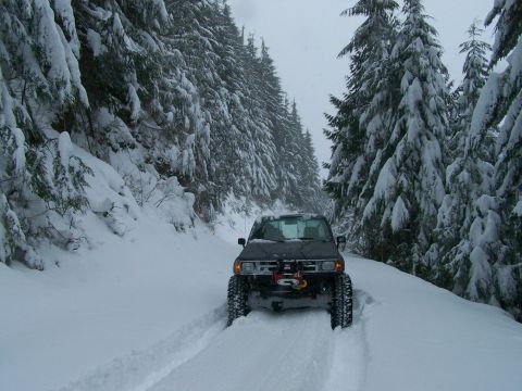 1988 Suzuki Samurai - A truck navigates a snowy forest road, its winch ready for action.