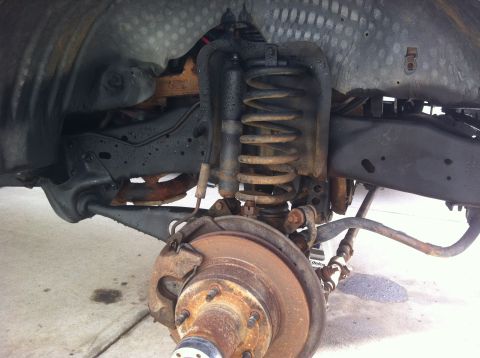 1991 Ford Bronco - Close-up view of a vehicle's front suspension and brake components, showing signs of wear and rust.