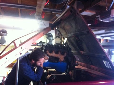 1968 Ford Bronco - An engine is being removed from a vehicle in a garage setting, with a person overseeing the process.
