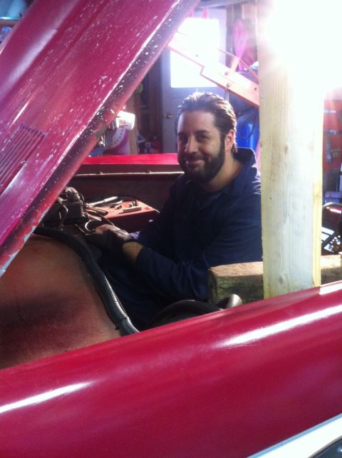 1968 Ford Bronco - Man works on the engine of a red 1968 Ford Bronco in a garage.