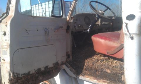 1973 Ford F-100 - The interior of an old truck shows a worn red seat and a dusty dashboard, with debris on the floor.