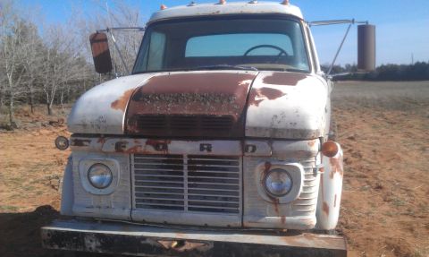 1973 Ford F-100 - This weathered 1967 Ford F-series truck sits in a field, showing significant rust on its hood and body panels.