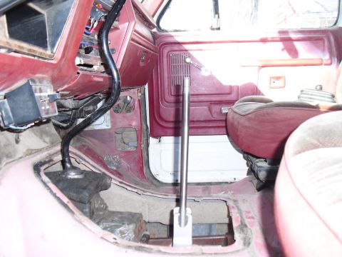 1986 Ford Bronco - Interior view of a vehicle's floor and dashboard, revealing a floor shifter and exposed metal components.