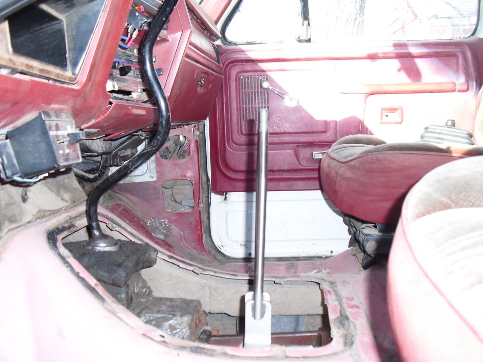 Vehicle interior with red upholstery and floor, showing a floor shifter and exposed metal