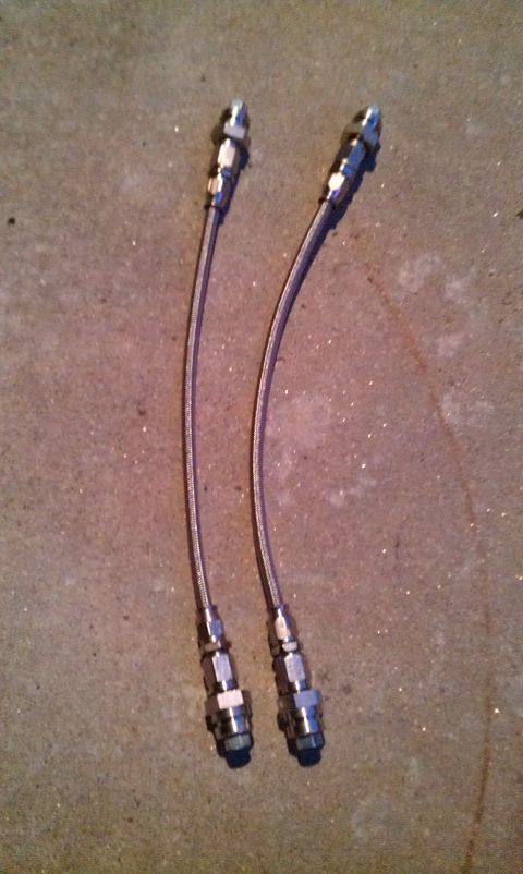 1992 Ford Ranger - Two braided metal brake lines with silver fittings are shown laid out on a concrete surface.