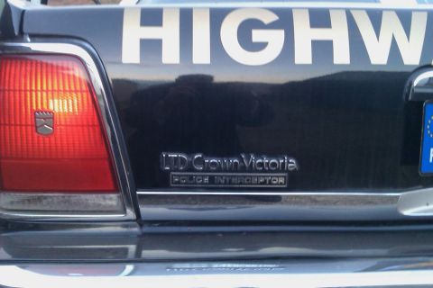 1991 Ford Crown Victoria - The rear of a black police car shows "LTD Crown Victoria" and "POLICE INTERCEPTOR" badging.