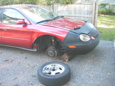 1997 Ford Taurus - This red 1997 Ford Taurus is missing a front wheel and has a car bra covering the front end.