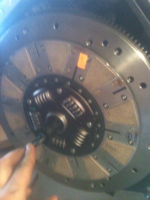 1993 Ford Bronco - A hand is shown adjusting a clutch disc, a critical component in a vehicle's drivetrain.