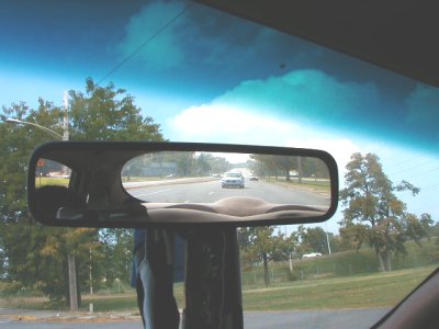 1997 Ford Taurus - A view through the rearview mirror of a car driving on a road with other vehicles visible.