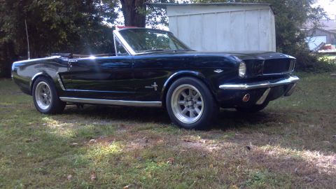 1965 Ford Mustang - Dark blue 1965 Ford Mustang convertible sits in a grassy yard.