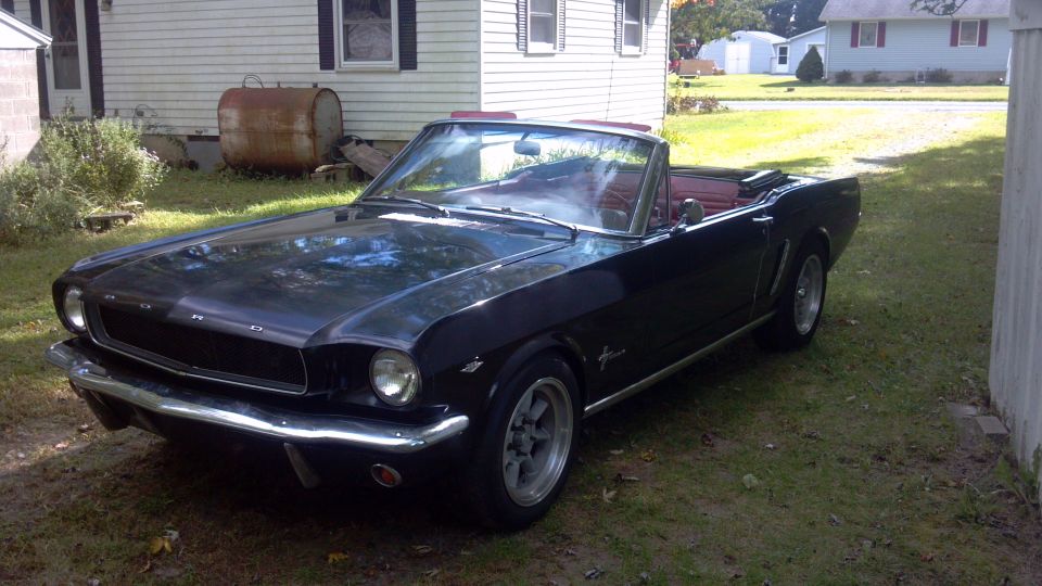 Black 1965 Ford Mustang convertible with red interior parked on grass
