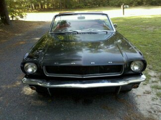 1965 Ford Mustang - A black 1965 Ford Mustang convertible is parked outdoors, viewed from the front.