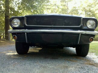 1965 Ford Mustang - Front view of a black 1965 Ford Mustang, its iconic grille and headlights.