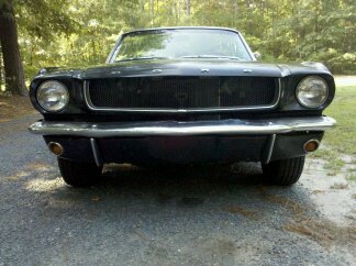 1965 Ford Mustang - Front view of a 1965 Ford Mustang with a black grille and chrome bumper.
