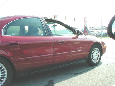 1997 Ford Taurus - Side profile of a red 1997 Ford Taurus sedan parked on a street.