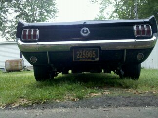 1965 Ford Mustang - Rear view of a 1965 Ford Mustang, showing its distinctive taillights and chrome bumper. The license plate reads 225965.