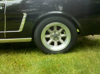1965 Ford Mustang - Close-up of the rear wheel and side panel of a 1965 Ford Mustang.