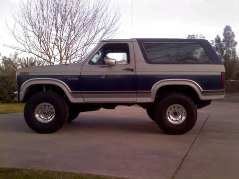 1986 Ford Bronco - Side view of a lifted 1986 Ford Bronco with custom wheels and tires.