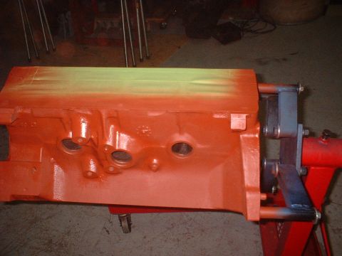 1969 Mercury Cyclone - Engine block painted orange with a section of yellow-green spray paint on top, mounted on a stand.