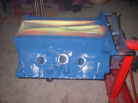 1969 Mercury Cyclone - A blue engine block is mounted on a red stand, partially covered with masking tape and showing streaks of orange and yellow paint.