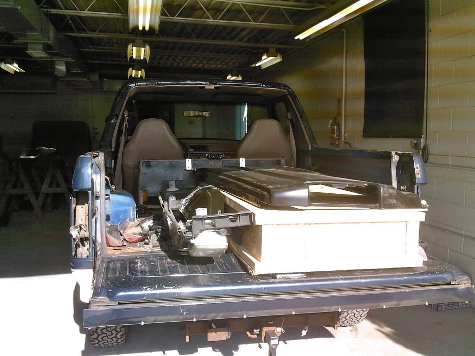 Rear of a truck with bed and interior partly removed in a garage