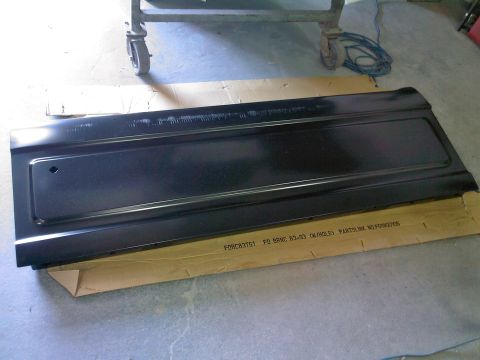 1992 Ford Bronco - A black tailgate panel, likely for a Ford Bronco from 1983-1993, is shown laid out on cardboard.
