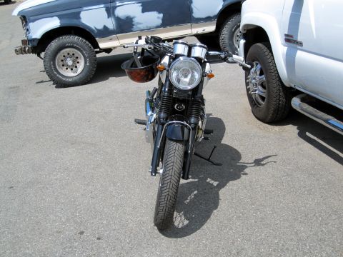 1992 Ford Bronco - A motorcycle is parked between two trucks, one of which is undergoing bodywork.