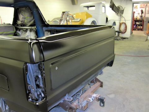 1992 Ford Bronco - A black Ford Bronco is being worked on in a garage, with another classic car in the background.
