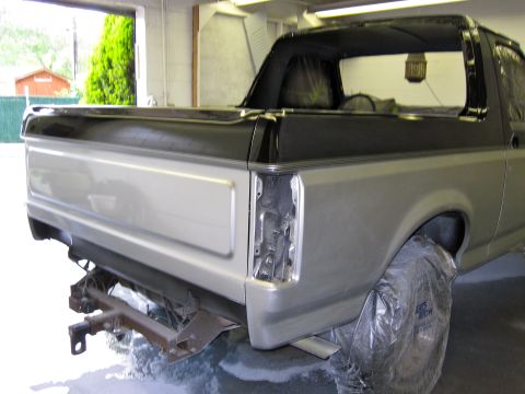 1992 Ford Bronco - Rear view of a 1992 Ford Bronco, showing the quarter panel and black trim, in a workshop.