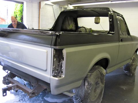 1992 Ford Bronco - A man works on a 1992 Ford Bronco in a garage, with the rear quarter panel disassembled.