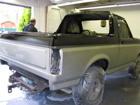 1992 Ford Bronco - A two-tone silver and black Ford Bronco is seen from the rear in a repair shop, with its bumper removed.