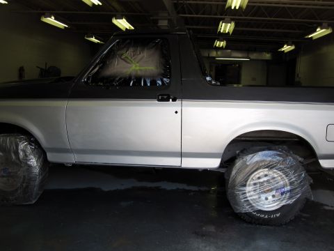 1992 Ford Bronco - A 1992 Ford Bronco is shown in a garage with its tires covered in plastic wrap.