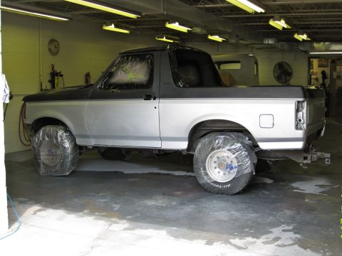 1992 Ford Bronco - This 1992 Ford Bronco is in a workshop, possibly undergoing repairs or a paint job, with its tires covered.