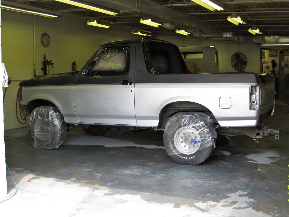 1992 Ford Bronco in a garage, tires covered, windows taped off