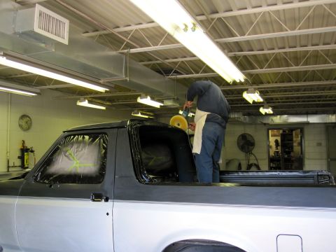 1992 Ford Bronco - A mechanic works on a 1992 Ford Bronco in a garage, with the vehicle covered in protective sheeting.
