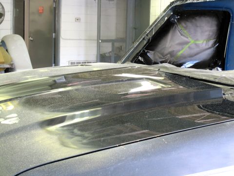 1992 Ford Bronco - A close-up view of a vehicle's hood scoop, covered in dust, with the windshield taped off for protection.