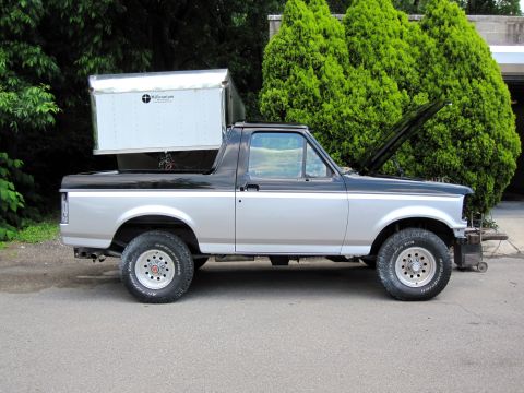 1992 Ford Bronco - This 1992 Ford Bronco has a cargo box mounted on its roof and the hood is open.
