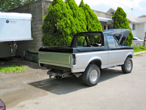 1992 Ford Bronco - This two-tone Ford Bronco has its hood up and the rear tailgate removed, parked outdoors.