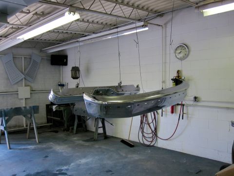 1992 Ford Bronco - Vehicle bumpers are suspended for repair or painting in a garage setting.