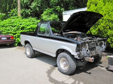 1992 Ford Bronco - This 1992 Ford Bronco is shown with its hood open and the front end disassembled, revealing the engine bay.