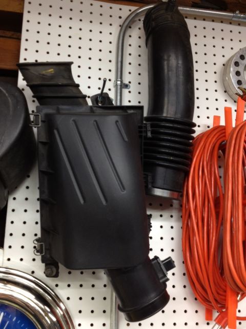 1998 Ford Crown Victoria - This is a vehicle part, likely an air filter box and intake hose, displayed on a pegboard.